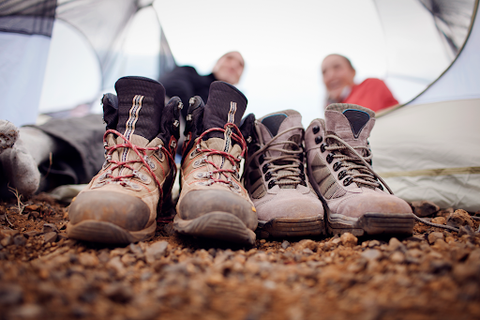 Some shoes outside the tent with two people inside the tent