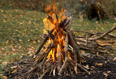 A fire made out of twigs and branches in an open space