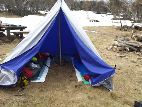 A blue central pole tent has a single pole in the middle