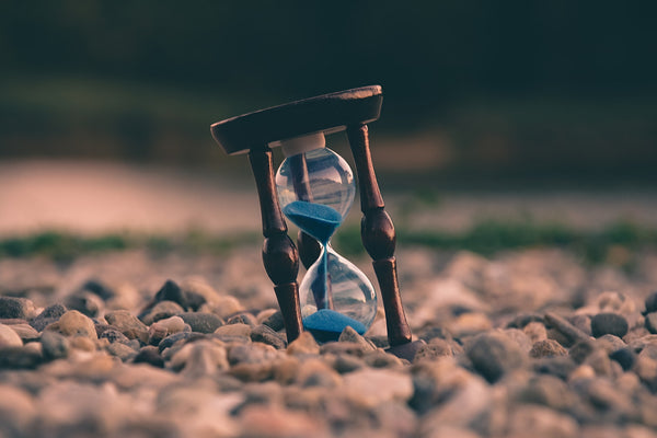 An hourglass nestled into a pebble beach.