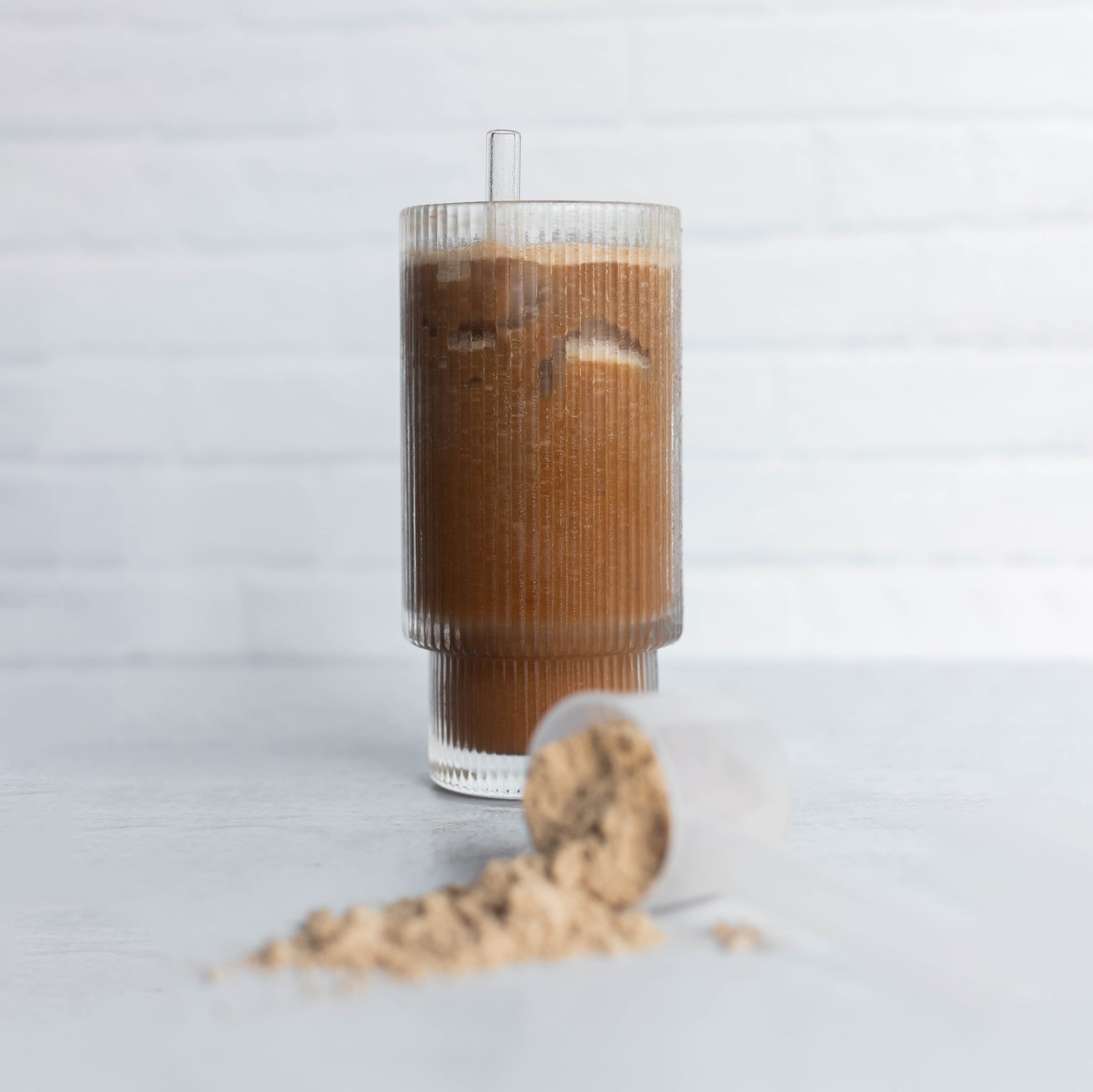 Frozen Latte Smoothie over Ice in Glass with Protein Powder Scoop