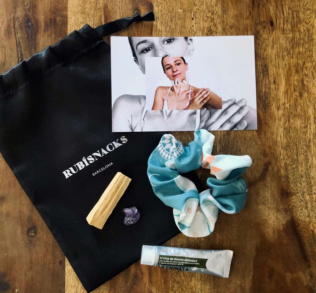 image of a luxe wellness giveaway bag - sustainable scrunchie, lotion, palo santo, in a satin bag.