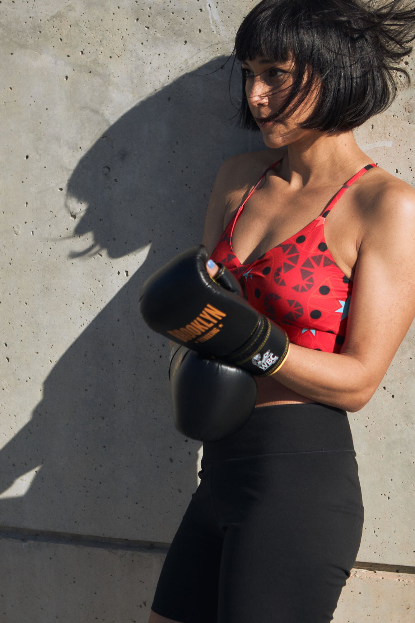 Woman in a red geometric sports bra and a black running tights with boxing gloves.