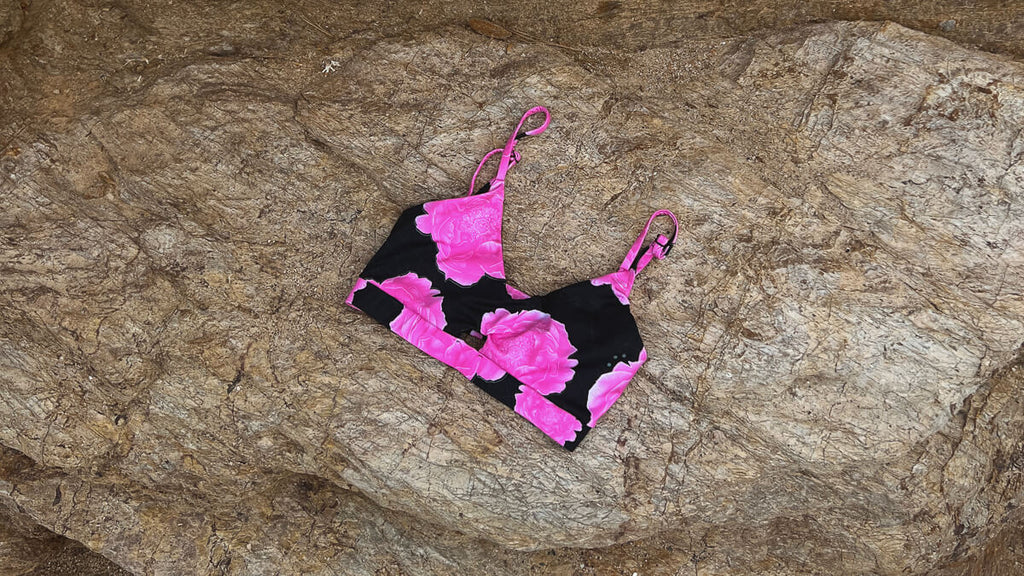 Pink floral sports bra with peony motif on a rock