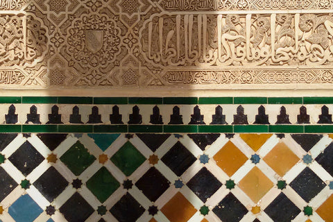 Arabic tiles from the Alhambra in Spain. White etchings and multicolored tiles with a shadow of a pillar