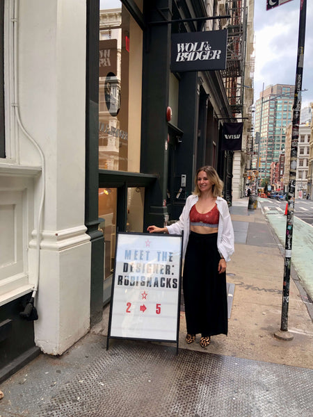 Independent designer, Rubisnacks standing next to a sign at a brand launch in SoHo NYC