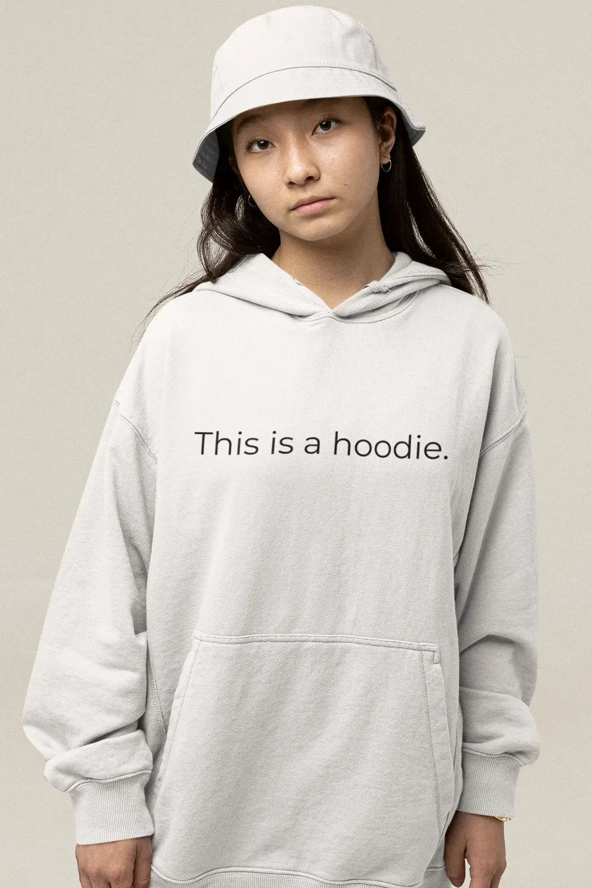 A teenage girl wearing a bucket hat and a hoodie with 'This is a hoodie.' on it.