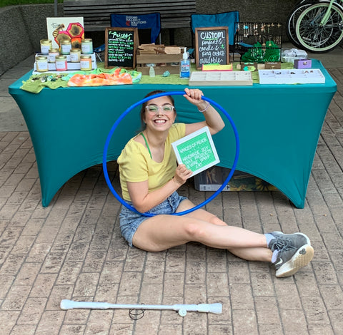 Artist Emily sitting in front of booth at craft fair