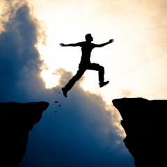 man jumping across cliffs