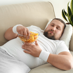 Man laying on couch eating snacks