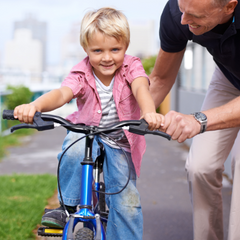 Kid riding bike with his dad