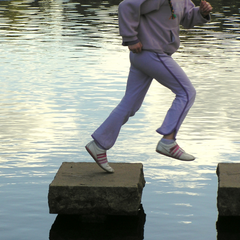 man leaping on stones in water