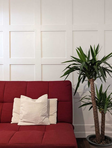 White shaker wall panelling behind a red sofa