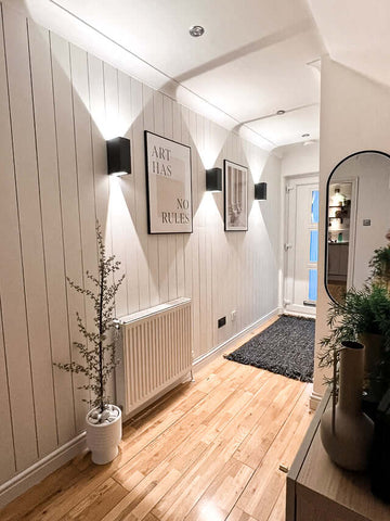 Shiplap panelling in hallway painted white, decorated with prints 