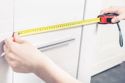 A person measuring a cabinet door. 