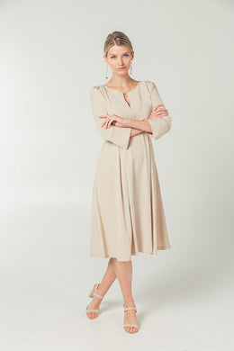 Beige maternity workwear dress with empire waist and designer breastfeeding access. Full feminine skirt, deep pockets, and structured sleeves. Petite and standards sizes. 