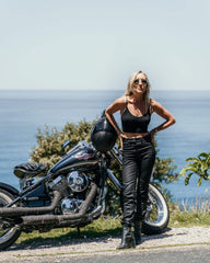 Photo of a woman next to a motorbike in Sydney wearing the Womens Venus Motorcycle Jeans, waxed black by Blackbird Motorcycle Wear