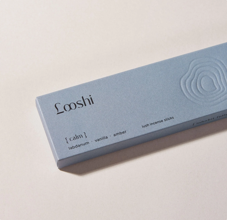 A blue incense stick box labeled 'Looshi' with scent description 'calm labdanum vanilla amber' on a light background.