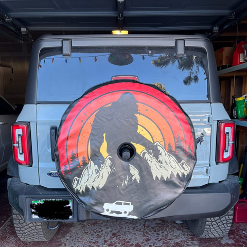 Retro Sasquatch and Ford Bronco spare tire cover on a gray Bronco