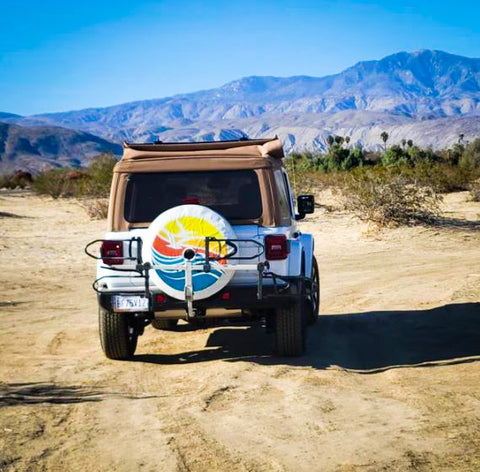 Beach waves and sunset with seagulls white vinyl spare tire cover on a white soft top Jeep Wrangler in the mountains.