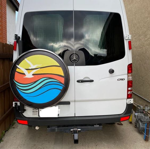 Sprinter van showing a colorful spare tire cover with a beach theme.