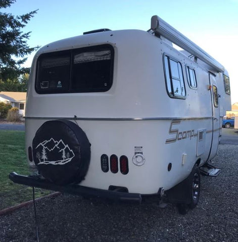 White camper with a black mountain custom spare tire cover