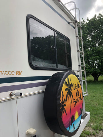 A RV spare tire cover of a tropical beach and the saying life is good.