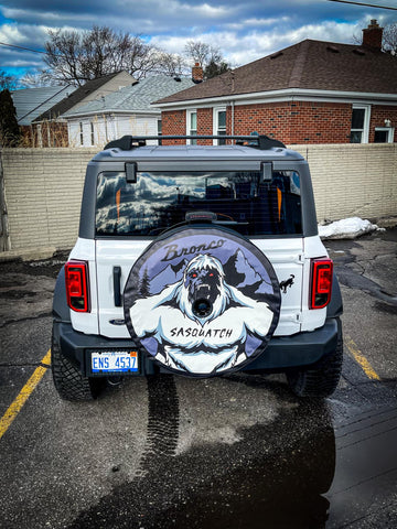 White Ford Bronco displaying a fierce Sasquatch spare tire cover design in purple and white