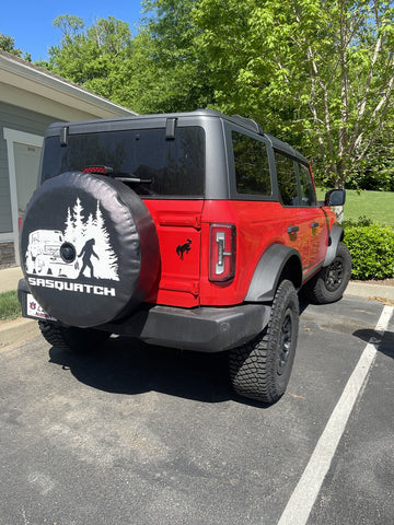 Sasquatch spare tire cover on a red ford bronco