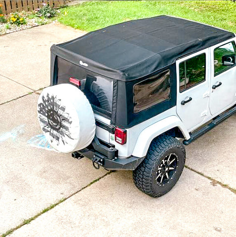 White Jeep with a white vinyl spare tire cover with a sunflower filled in as an American flag