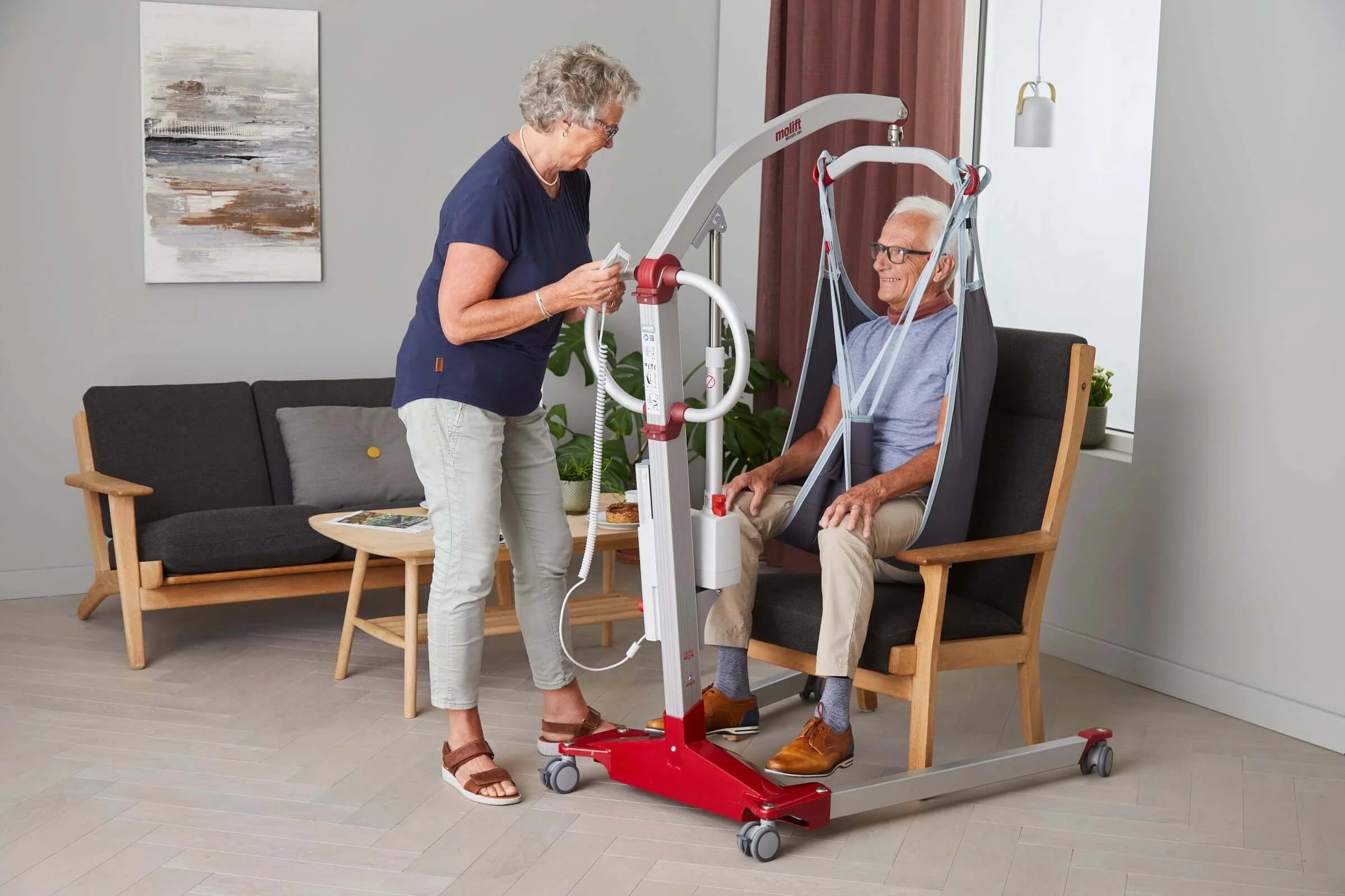 RgoSling MediumBack Padded Patient Sling used by man in a chair and his nurse helping