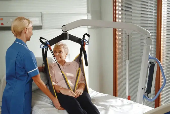lady using hoyer presence patient lift in bed with nurse helping her
