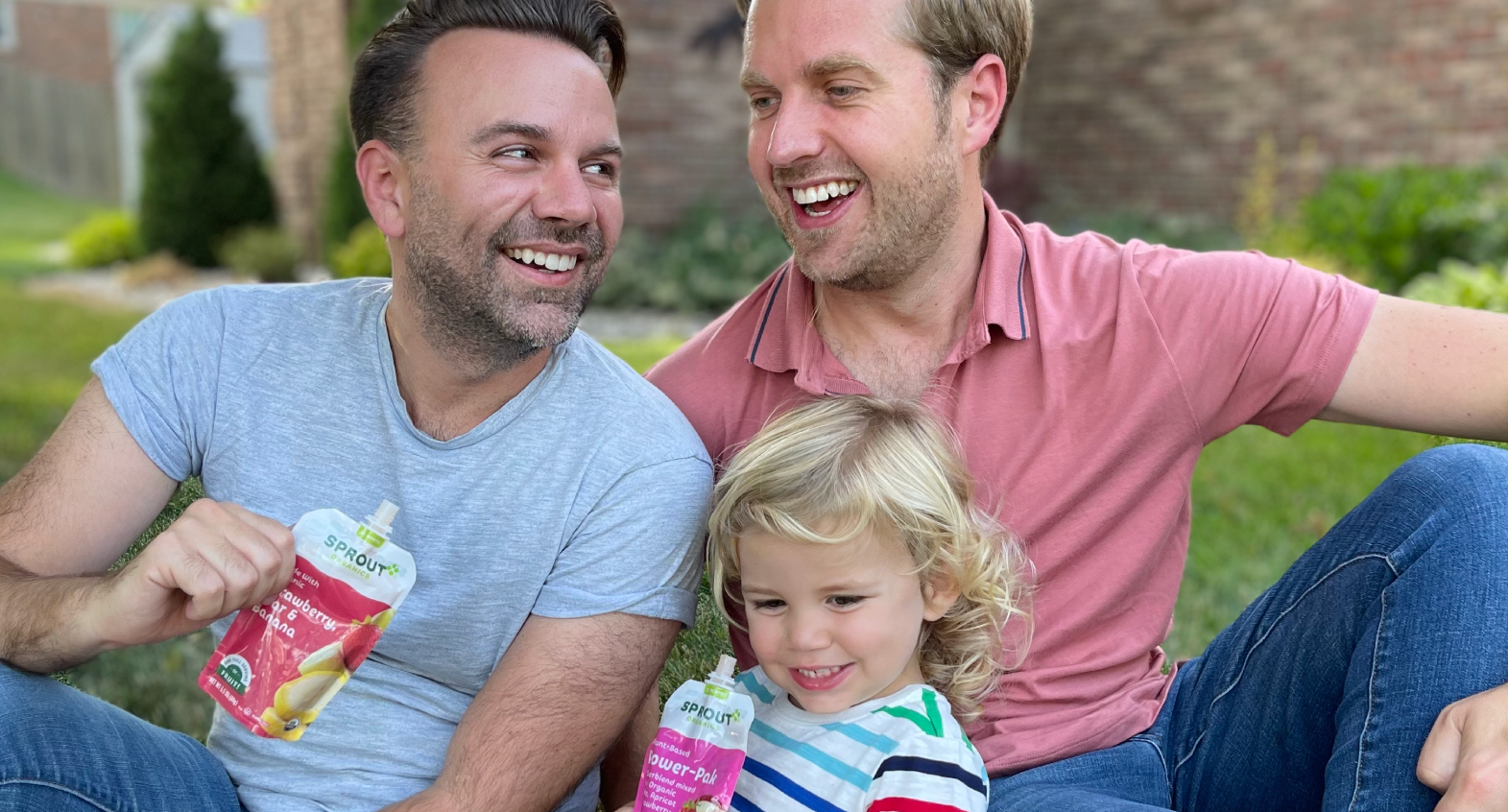 parents and child sit smiling and enjoying sprout organics pouches