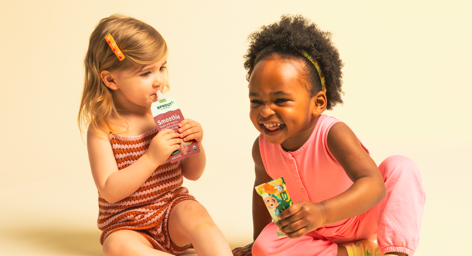 two children on a yellow background holding sprout products