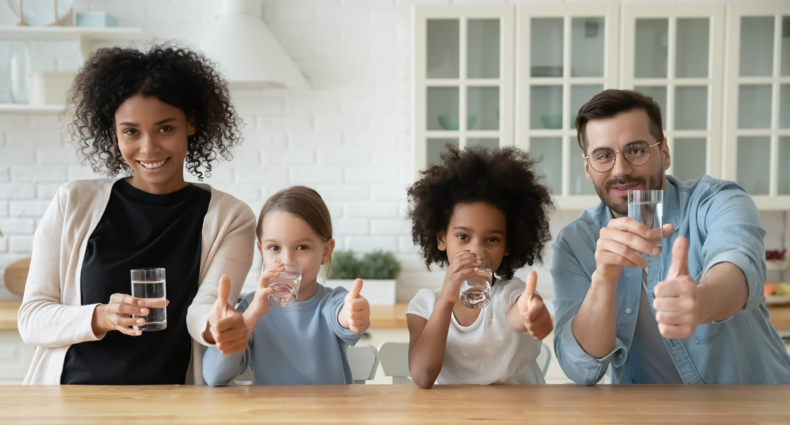 a family in the kitchen smiling with glasses of water