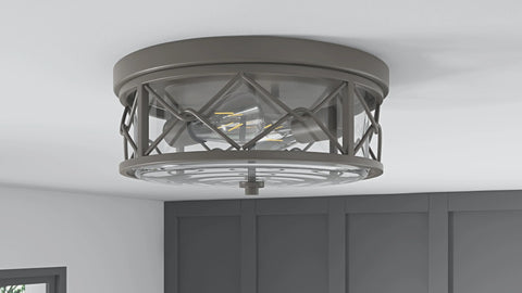 A gray, round ceiling light fixture with a clear glass shade and a criss-cross metal design. The exposed filament bulbs are visible inside.