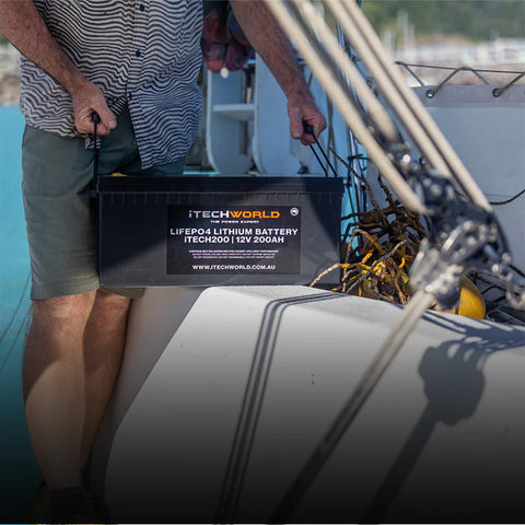 A photo of a man holding an iTech200 Deep Cycle Lithium Battery whilst inside of a boat.