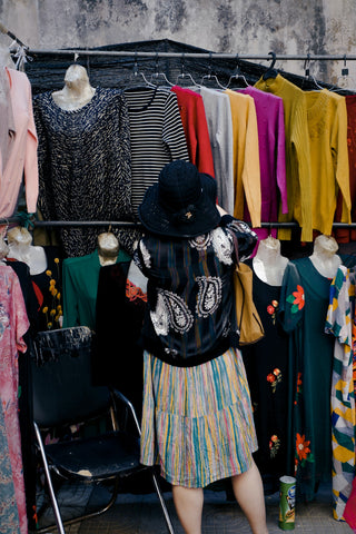 Woman browsing colourful shirts at thrift shop