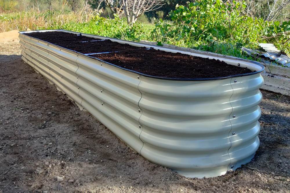 A white 17-inch tall metal garden bed fills soil placed on soil