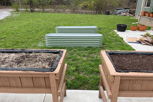 two wood raised garden beds and two metal raised garden beds in garden