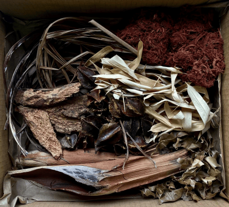 A box of red, brown, and white aquatic botanicals that will grow an abundance of biofilms in blackwater aquariums at Betta Botanicals.