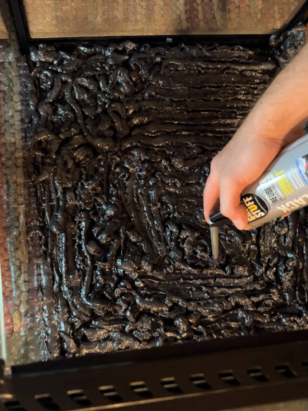 A terrarium on the ground with a can of Great Stuff Spray foam being applied to the back.