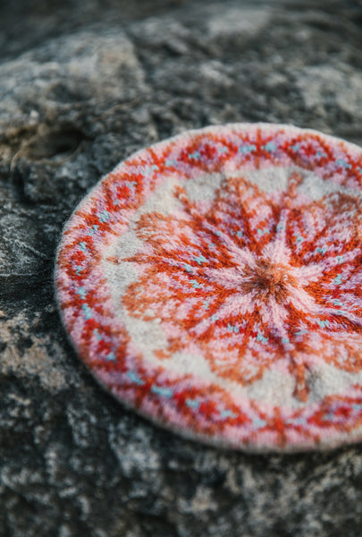 The Buness hat in red and white, laying on a rocky surface.