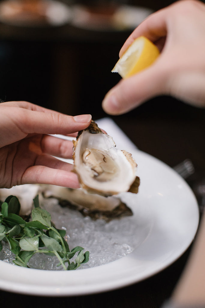 A close-up image of squeezing lemon onto a mussel.