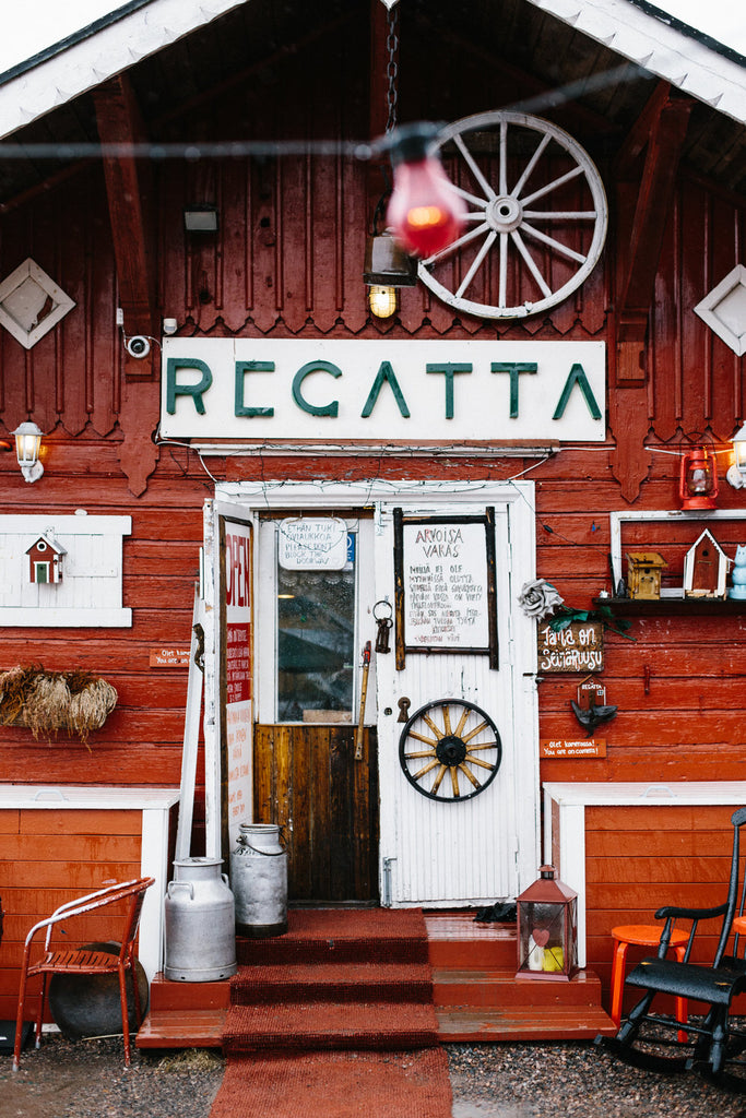 A photograph of Café Regatta from the front: a quirky, red and white little building, adorned with rustic elements.