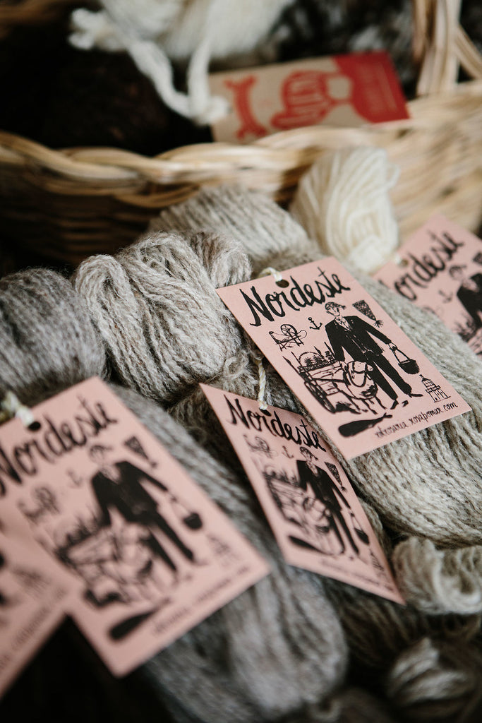 Image of yarn goods in Retrosaria: a pile of grey Nordeste skeins in front of a woven basket.