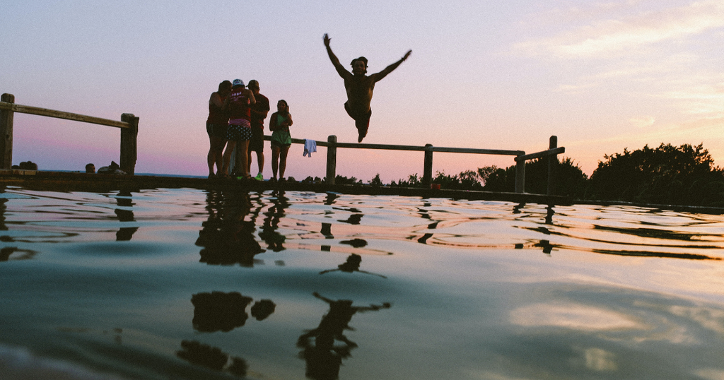 Man with friends relaxed and diving into water. Showing that ashwagandha improves your mood