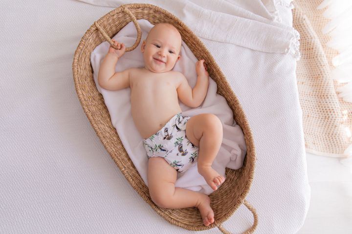 Baby wearing modern cloth nappy in rattan changing basket