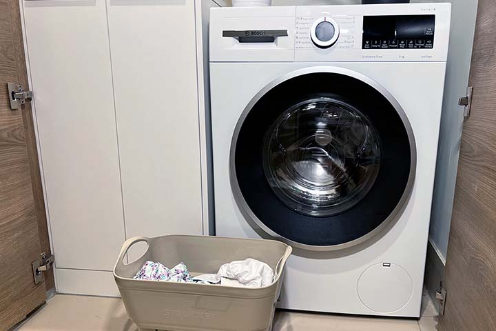 Washing machine with basket of cloth nappies in front of it