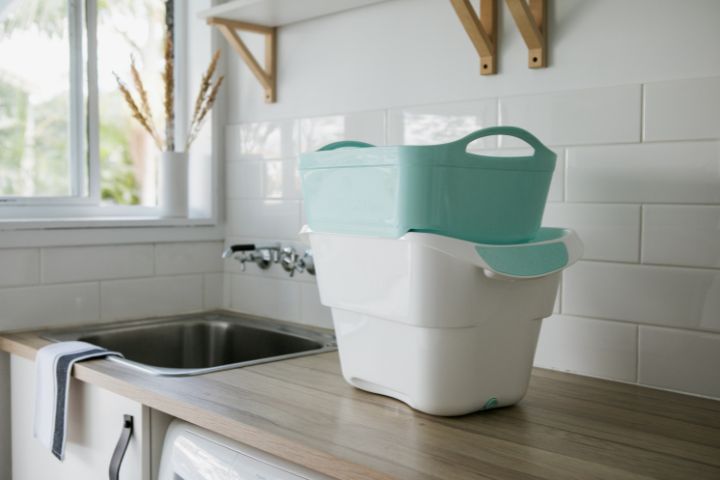 Aqua coloured strucket (strainer/bucket) next to clean and tidy laundry sink